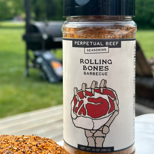 A plastic jar of Rolling Bones Barbecue Perpetual Beef dry rub with a label that features a hand holding a steak, with a background suggestive of an outdoor grilling setting.