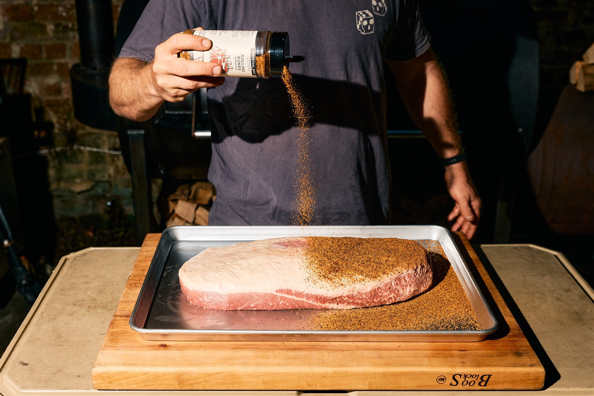 Bottle of Rolling Bones BBQ Perpetual Beef dry rub seasoning on a brisket.
