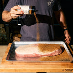 Bottle of Rolling Bones BBQ Perpetual Beef dry rub seasoning on a brisket.