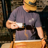 Bottle of Rolling Bones BBQ Perpetual Beef dry rub seasoning on a brisket.