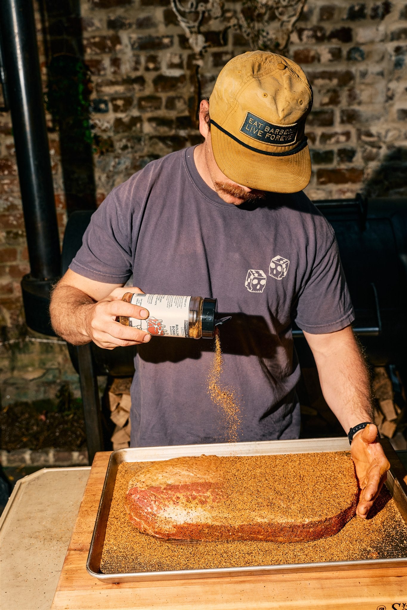 Bottle of Rolling Bones BBQ Perpetual Beef dry rub seasoning on a brisket.