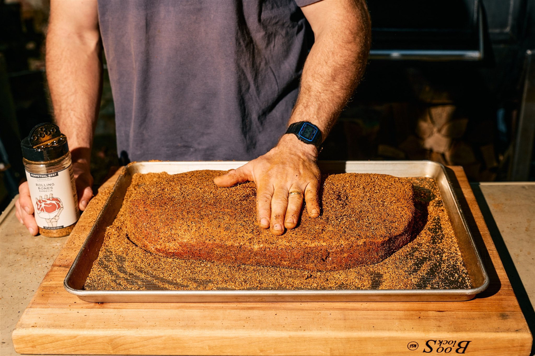 Bottle of Rolling Bones BBQ Perpetual Beef dry rub seasoning on a brisket.